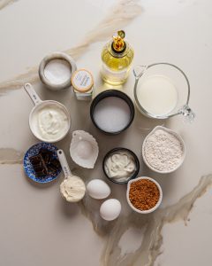 Low calorie chocolate cake ingredients including Greek yogurt, cocoa powder, erythritol, eggs, and whole wheat flour on a kitchen counter