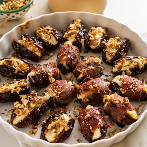 Baked healthy cheese stuffed dates with walnuts and prosciutto in a baking dish