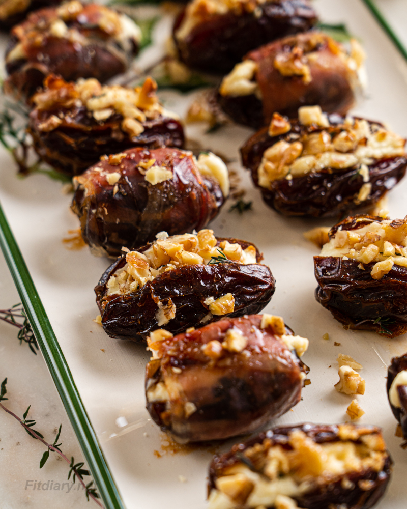 Healthy cheese stuffed dates served on a plate, drizzled with honey and garnished with herbs