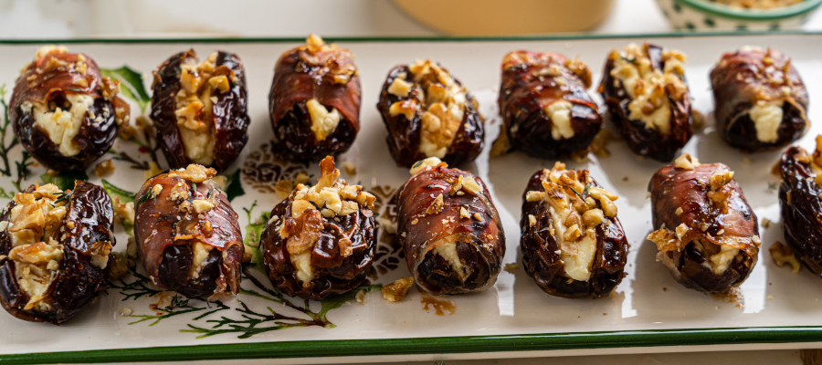 Healthy cheese stuffed dates served on a plate, drizzled with honey and garnished with herbs
