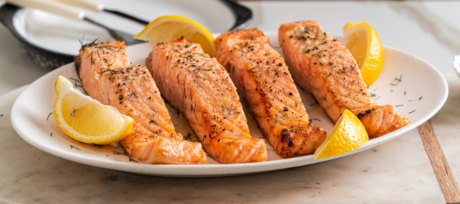 Juicy air fryer salmon served on a plate with fresh lemon wedges and herbs